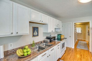Une cuisine avec des meubles blancs, un plan de travail en granit, un évier, un grille-pain et un four à micro-ondes.