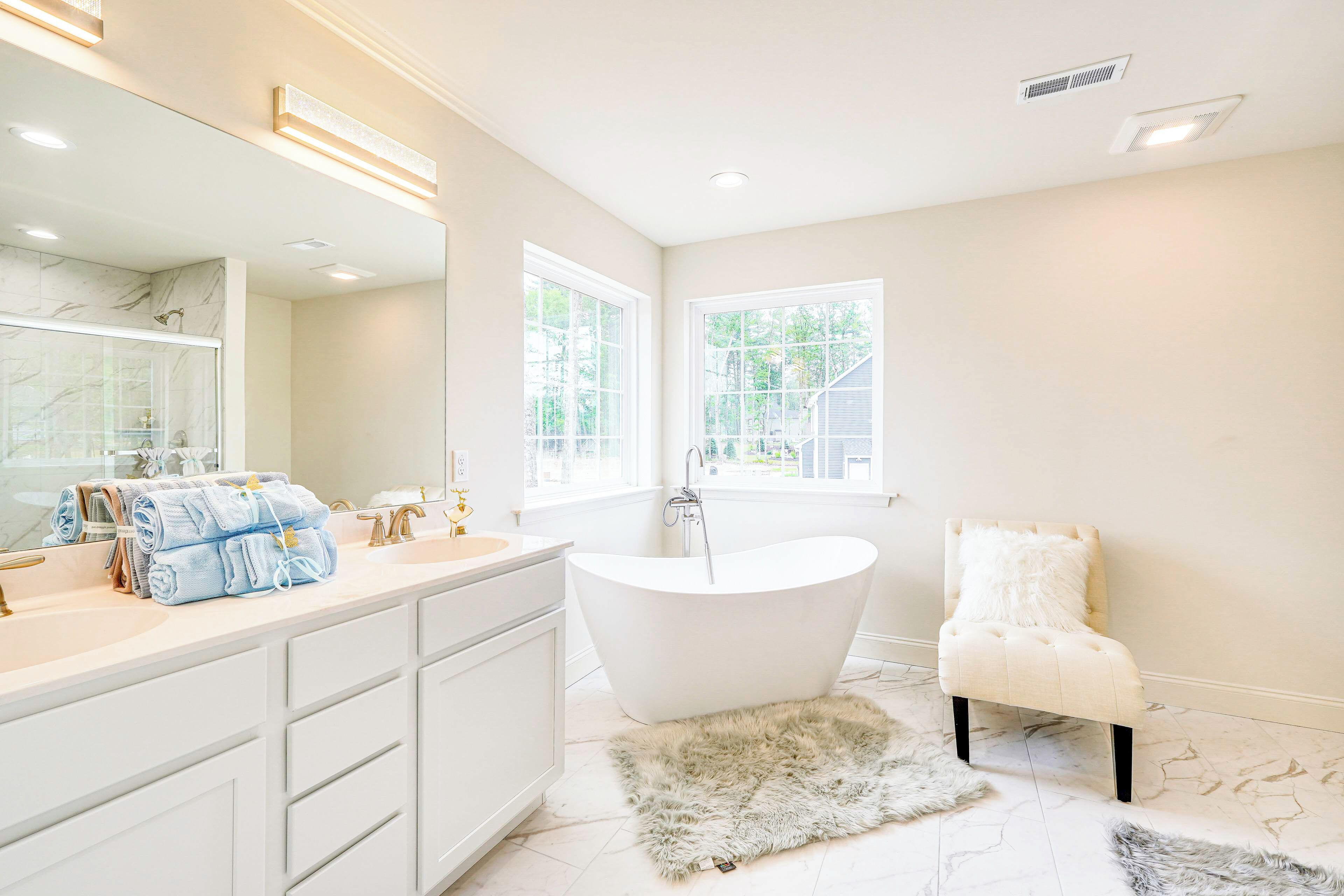 Une salle de bain moderne avec une baignoire sur pieds, un grand miroir et un meuble-lavabo.