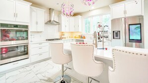 A modern kitchen with white cabinets, stainless steel appliances, and two bar stools. - Hike, Sip & Ski: Spacious Poconos Home (Kunkletown)