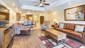 A spacious living room with a brown leather sofa, a wooden coffee table, and a ceiling fan. - Riverfront Bullhead City Condo Near Casinos! (Bullhead City)