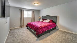 A bedroom with a bed, a window with curtains, a ceiling light, and a wall-mounted TV. - Spacious Southfield Home w/ Patio & Yard! (Southfield)