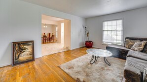 A spacious living room with hardwood flooring, a round coffee table, a sofa, and a framed picture on the wall. - Spacious Southfield Home w/ Patio & Yard! (Southfield)