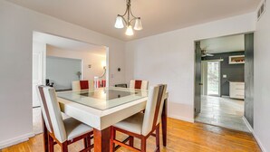 A dining area with a glass-top table, wooden chairs, and a chandelier. - Spacious Southfield Home w/ Patio & Yard! (Southfield)
