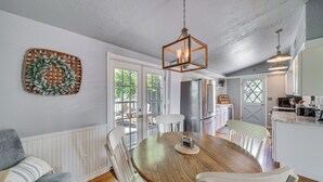 A dining area with a wooden table and white chairs, a hanging light fixture, and a decorative wreath on the wall. - On-site River Access: Medina Vacation Rental (Medina)