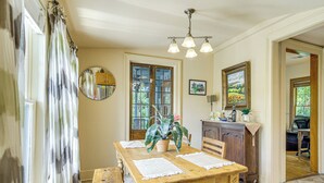 A dining area with a wooden table, chairs, a potted plant, and a chandelier. - Eclectic Mandeville Home: Walk to Lakefront Park (Mandeville)