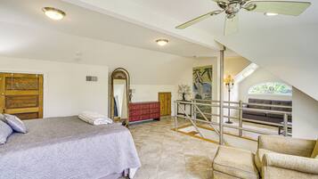 Un dormitorio con cama, tocador, espejo y una escalera que lleva a un balcón.