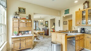 A spacious kitchen with wooden cabinets, a central island, and a dining area. - Eclectic Mandeville Home: Walk to Lakefront Park (Mandeville)