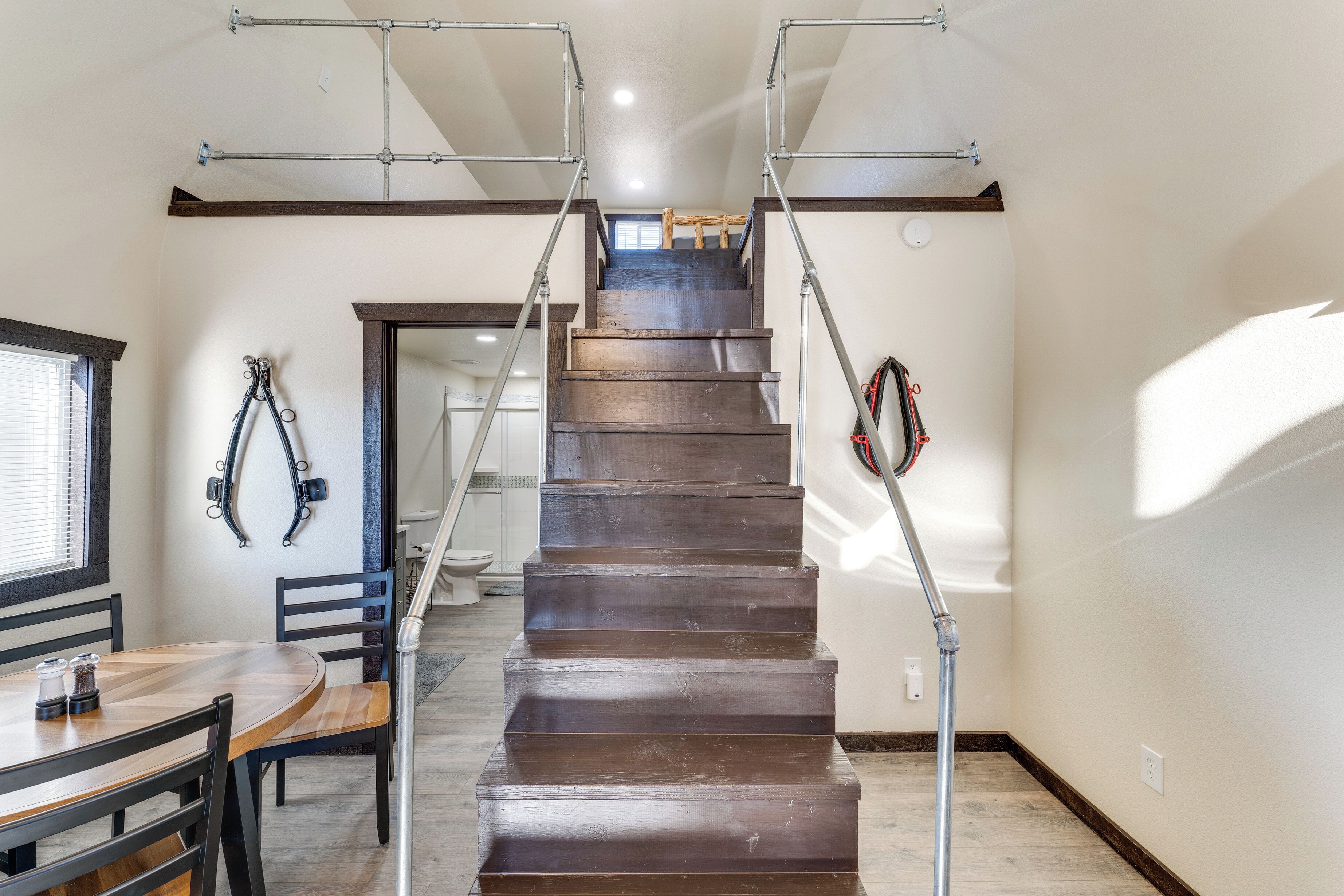 A wooden staircase with metal handrails, leading to an upper floor.