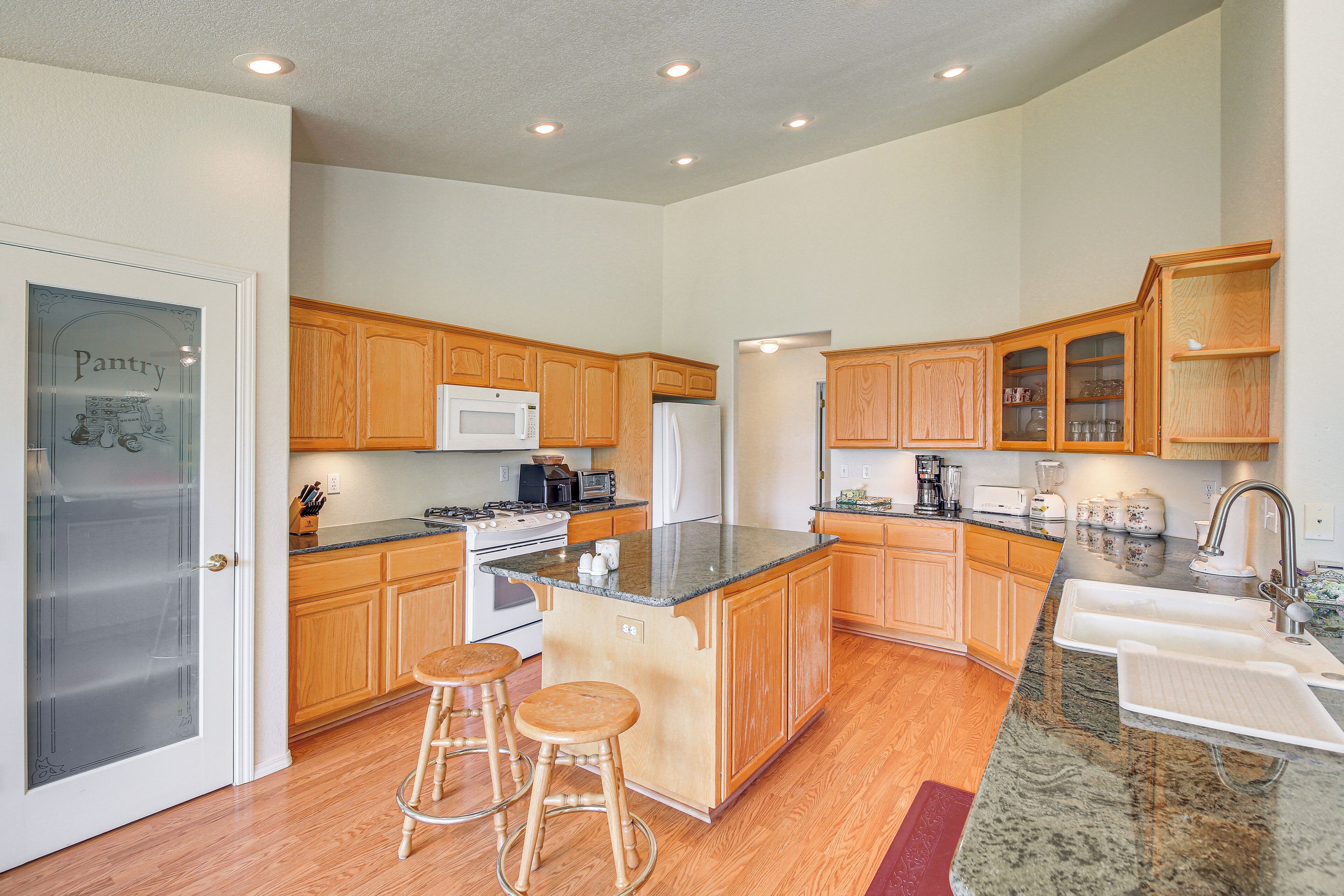 A modern kitchen with wooden cabinets, a granite countertop, a refrigerator, a microwave, and a sink.