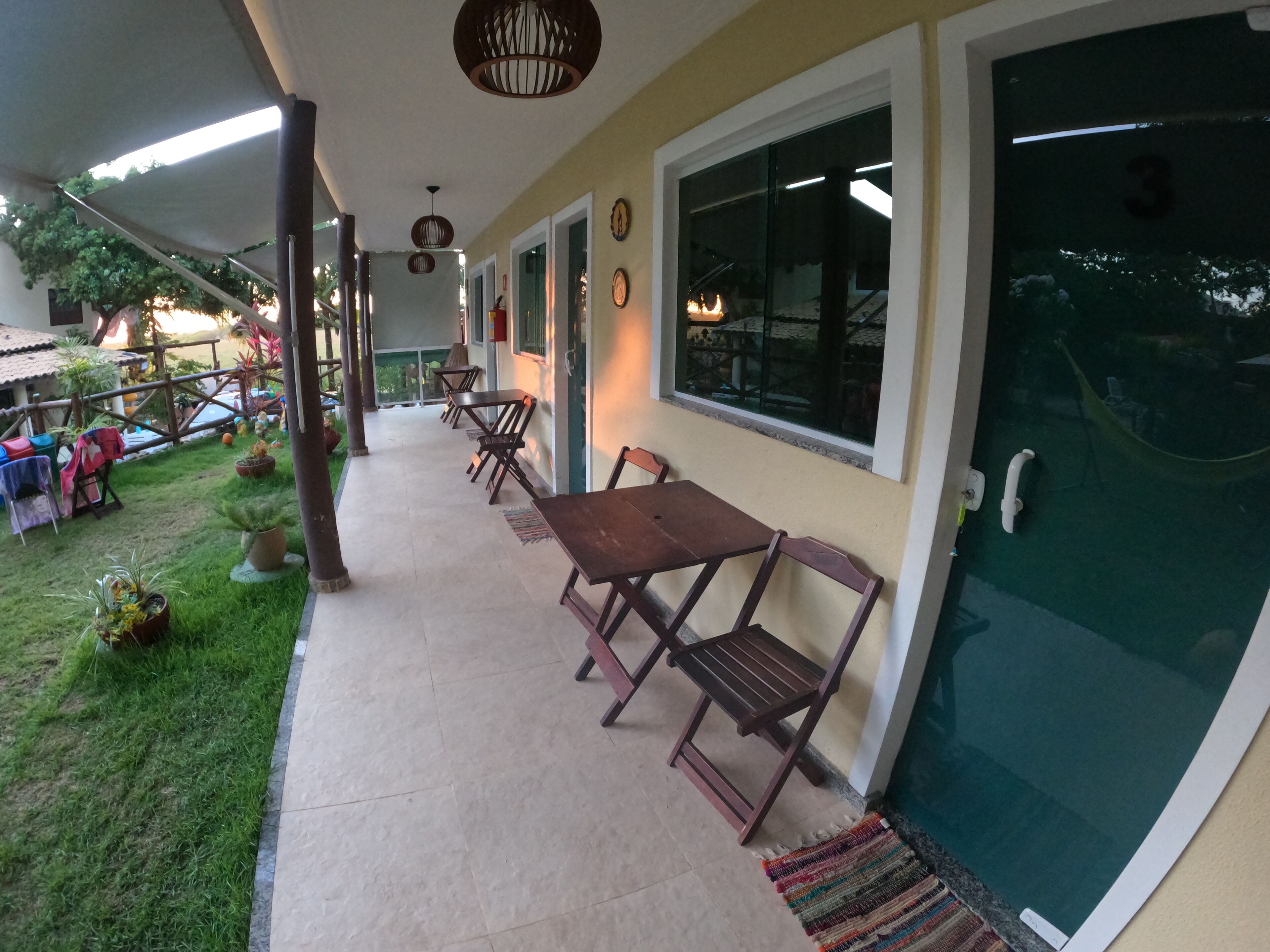 Ein Terrassenbereich im Freien mit einem langen Tisch und Stühlen, umgeben von Topfpflanzen und einem Swimmingpool.