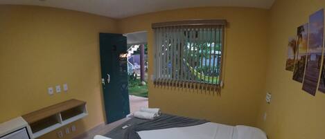 A hotel room with a bed, a desk, and a window with blinds.