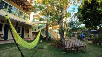 A courtyard with a hammock, a wooden bench, and a tree.