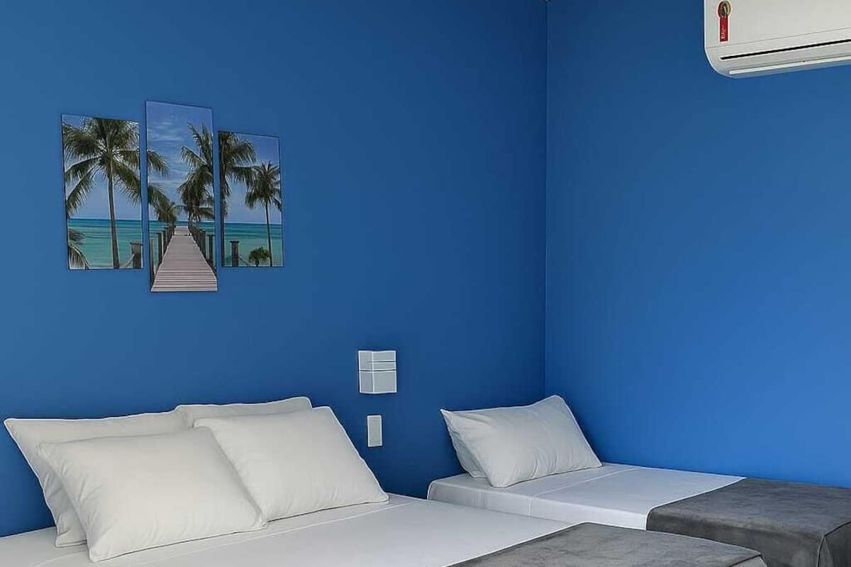 Ein Zimmer mit zwei Betten, einer blauen Wand und einem Kunstwerk zum Thema Strand.