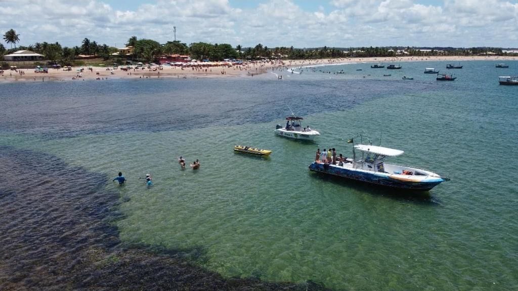 Une plage avec des bateaux, une eau claire et un rivage sablonneux.