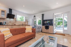 Una cocina moderna con un televisor de pantalla plana, un sofá con cojines estampados y una mesa de centro de vidrio.
