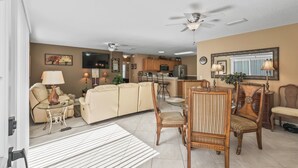 Una sala de estar moderna con un sofá, sillas, una mesa de comedor y una cocina al fondo.