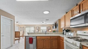 Una cocina moderna con armarios de madera, electrodomésticos de acero inoxidable y suelo de baldosas.