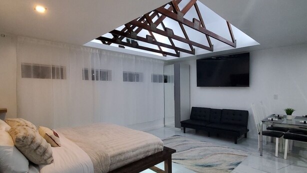 Ein modernes Schlafzimmer mit Bett, einer Sitzecke, einem Fernseher und einem Essbereich.