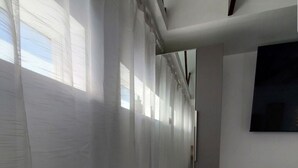 Ein moderner Flur mit weißen Wänden, einer schwarzen Bank und einem großen Bildschirm.