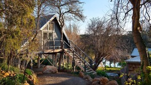 A wooden cabin with a staircase leading to a deck, surrounded by trees and a gravel path. - The Falls at Lake Werona (Werona)