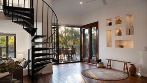 A modern interior with a spiral staircase, a dining area with outdoor views, and built-in shelves with decorative items. - The Falls at Lake Werona (Werona)