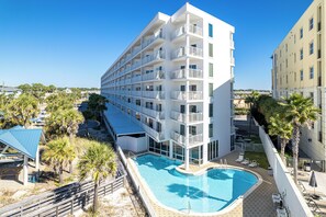 A multi-story hotel with a pool area, including a swimming pool and sun loungers.