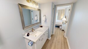Une salle de bain avec un lavabo en marbre, un grand miroir et un porte-rouleau de papier toilette.