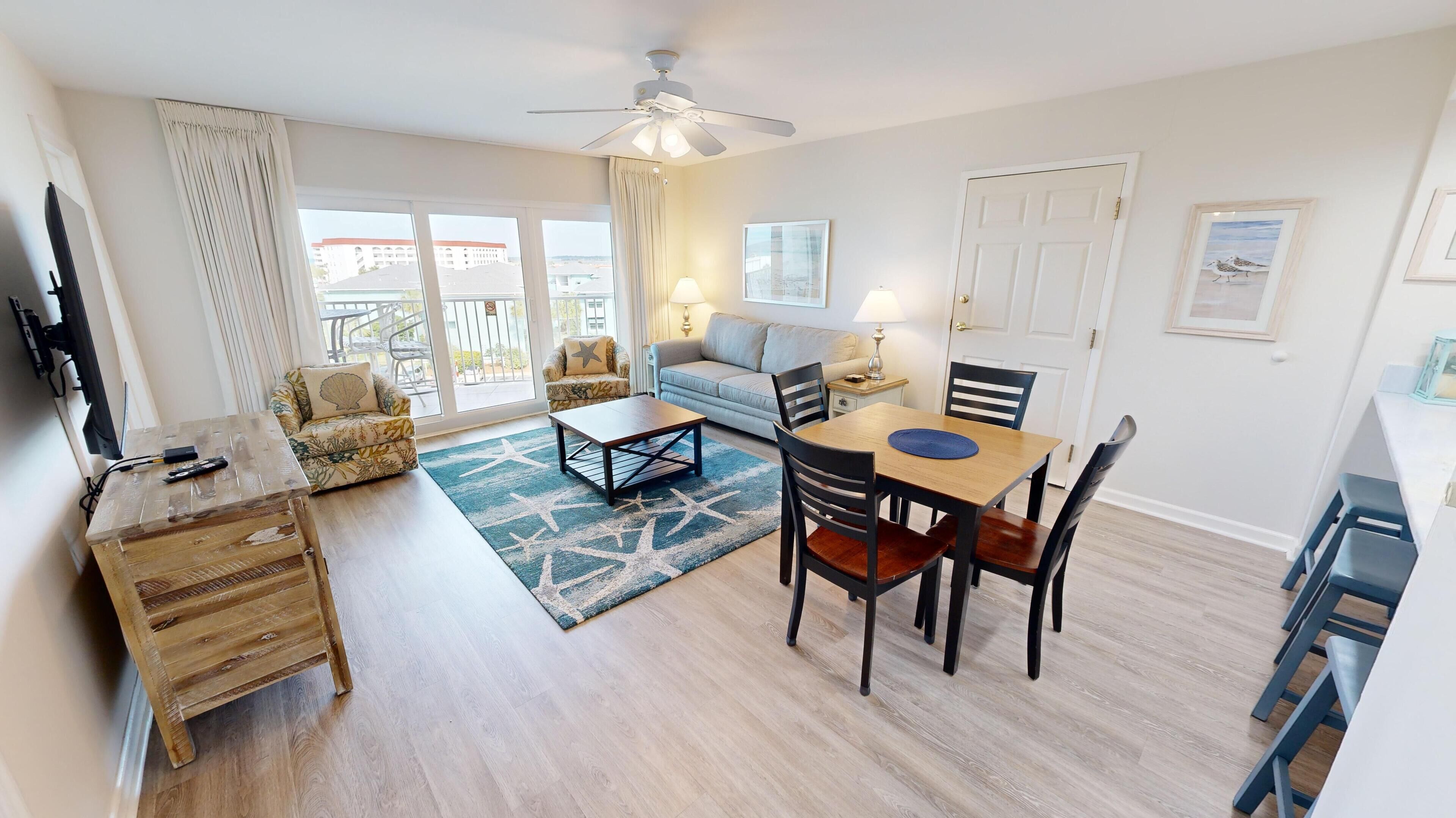 A spacious living area with a dining table, chairs, a sofa, and a TV.