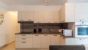 Une cuisine moderne avec des meubles de couleur bois clair, un plan de travail noir, un four à micro-ondes et un four encastré.
