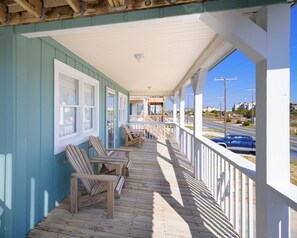 A wooden deck with chairs and a railing, overlooking a road. - Modern, Dogs Allowed, Across from Beach, Central Location, KD1514 (Kill Devil Hills)
