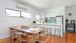 A modern kitchen with white cabinets, a wooden dining table with metal chairs, and a small bar area.