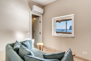 Un salon moderne avec un canapé, une petite table ronde et une fenêtre donnant sur la mer.