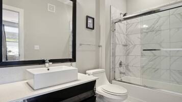 Un bagno con un lavandino bianco, un water e una cabina doccia in vetro.