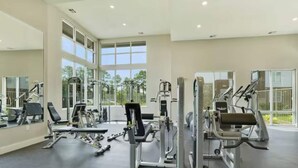 Ett rymligt gym med olika träningsmaskiner, stora fönster och en spegel.