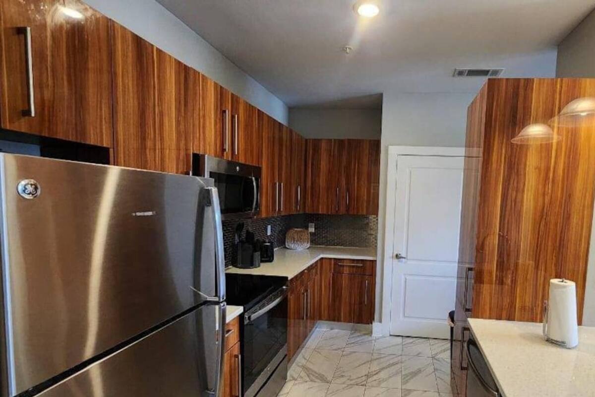 A modern kitchen with wooden cabinets, stainless steel appliances, and a white countertop.