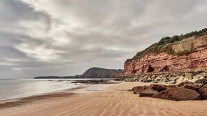 A beach with a rocky cliff and a calm sea. - Little Buckley Peaceful Family Retreat Nr Sidmouth (Sidbury)