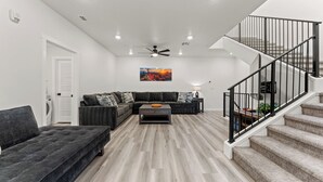 Ein modernes Wohnzimmer mit einer Eckcouch, einem Couchtisch und einer Treppe mit Geländer.