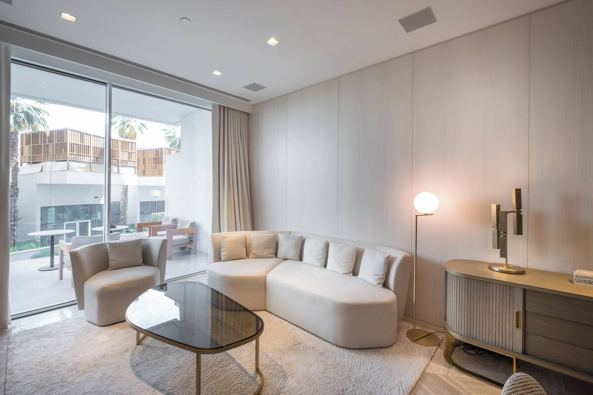 A modern living room with a sectional sofa, a glass coffee table, and a floor lamp.
