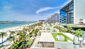Un hotel frente a la playa con varias construcciones, una playa y palmeras.