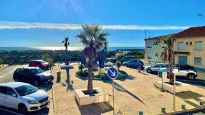 A parking area with cars, palm trees, and a clear sky. - Les Pieds Dans L'eau (Valras-Plage)