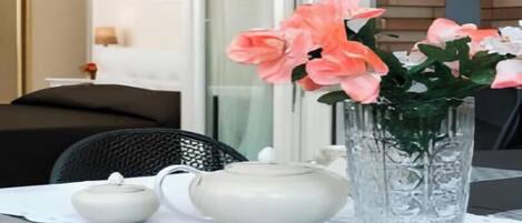 A table with a teapot, a small pot, and a vase with flowers.