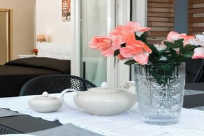 A table with a teapot, a small pot, and a vase with flowers.