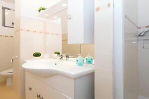 A modern bathroom with a white sink, mirror, and cabinets.
