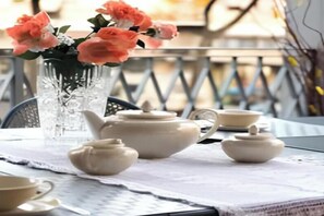 A table set with teapots and a vase of flowers on a balcony.