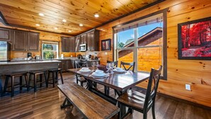 A wooden interior with a kitchen, dining area, and large windows.