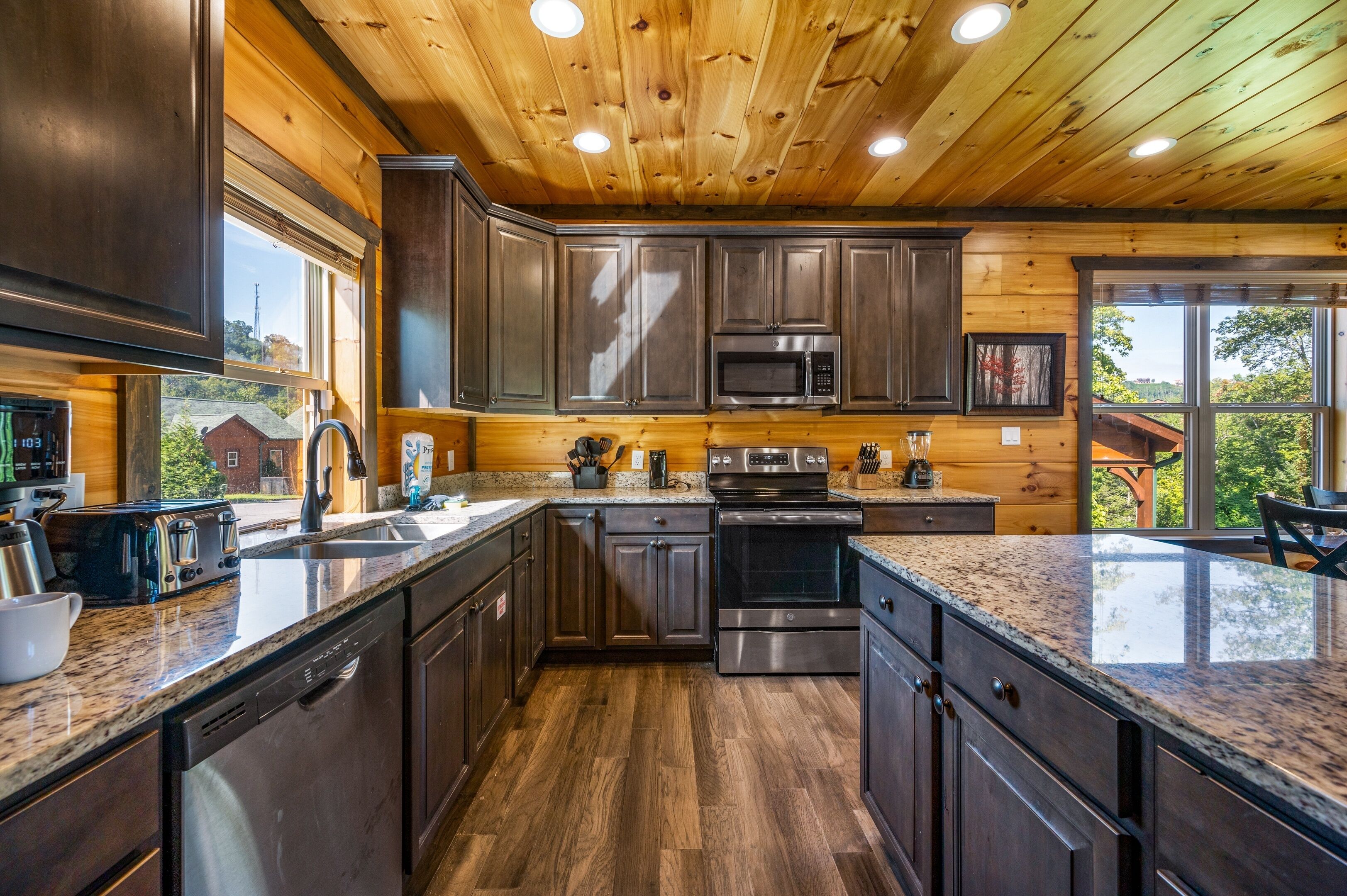 A modern kitchen with dark wood cabinets, stainless steel appliances, and granite countertops.