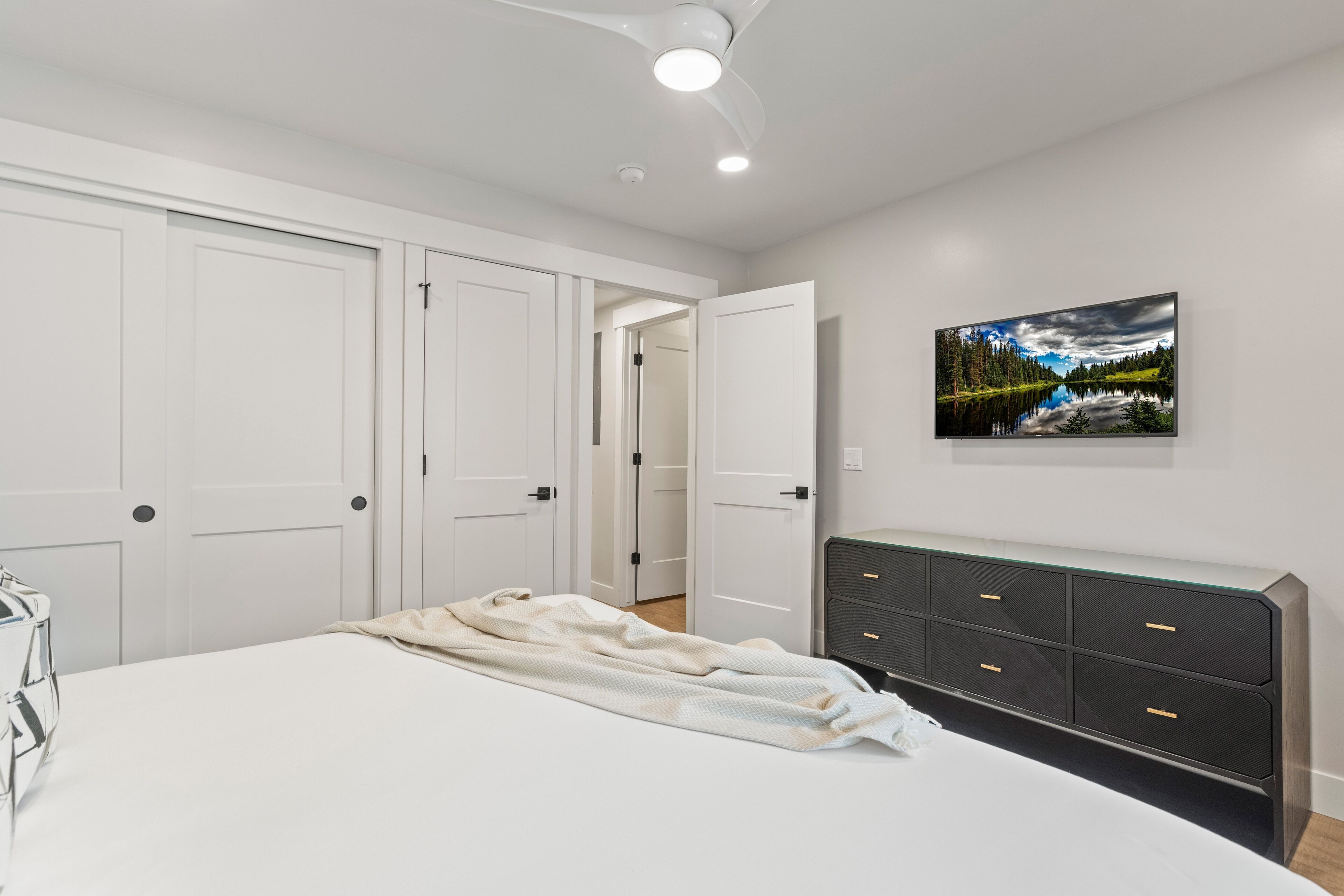 A bedroom with a bed, a dresser, and a painting on the wall.