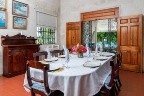 A dining room with a round table set for four, wooden chairs, a white tablecloth, and a vase of flowers. - Clearwater 4 Bedroom Home (Gibbes)