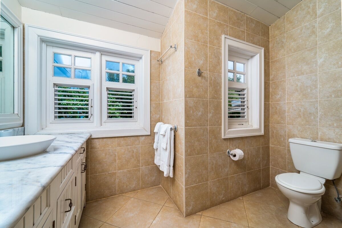 A bathroom with a bathtub, toilet, and window with blinds.