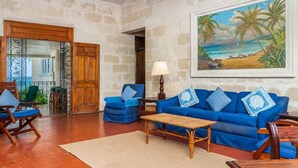Ein Zimmer mit einer Steinsandsteinwand, einem blauen Sofagarnitur, einem Holztisch und einem Gemälde, das eine Strandansicht zeigt.